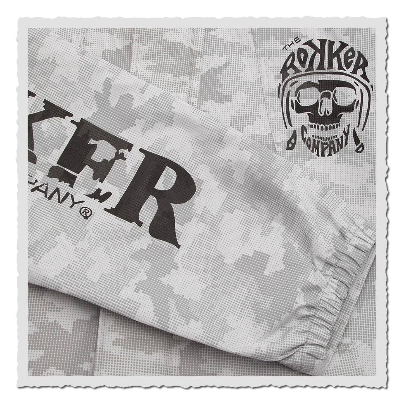 Detail am Ärmel mit schwarzem Print auf grauem Camomuster, elastischer Abschluss und Nahtführung in Nahaufnahme.